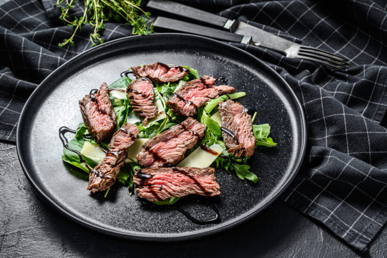 steak salad with spinach arugula and sliced beef striploin steak black background top view 190994259
